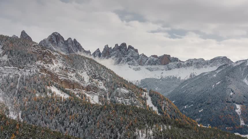 Clouds move over snowcapped mountains