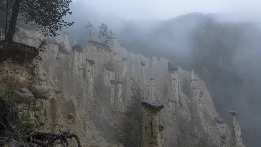 Natural landscape with sharp cliffs with rocks and conifers and fog around