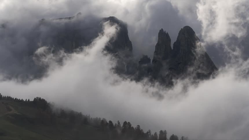 Dramatic landscape with mountain peaks emerging from a dense cloud layer with mist