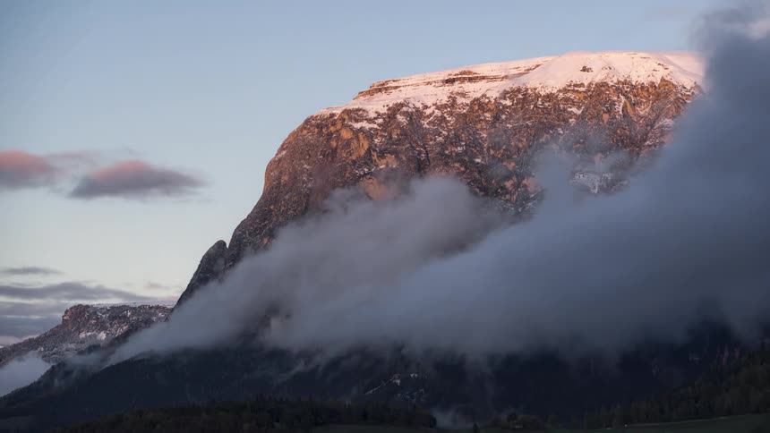 Low clouds passing next to a snowy mountain