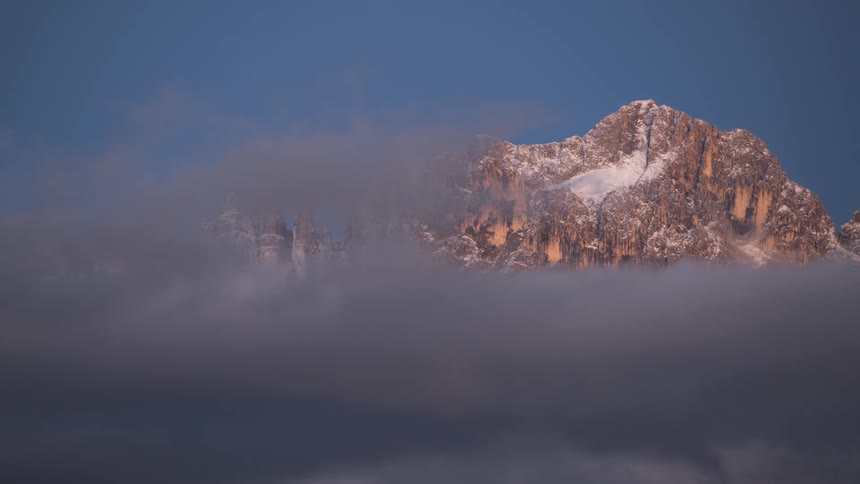 The towering snowcapped mountain peak pierces through the clouds