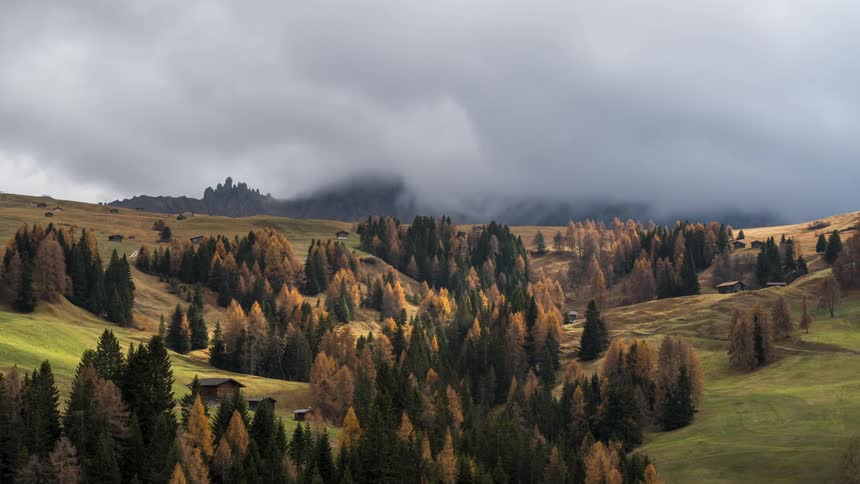 Trees turning colors around a rural community as clouds billow in overhead