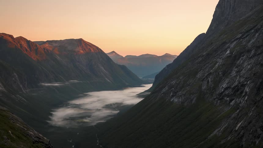 Landscape of a mountainous valley with low clouds and the dawning day