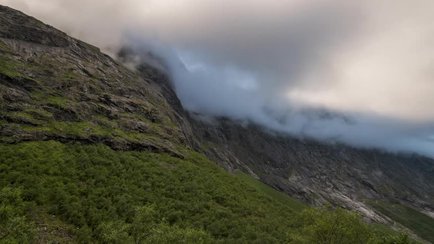 Dense clouds passing above rocky mountains