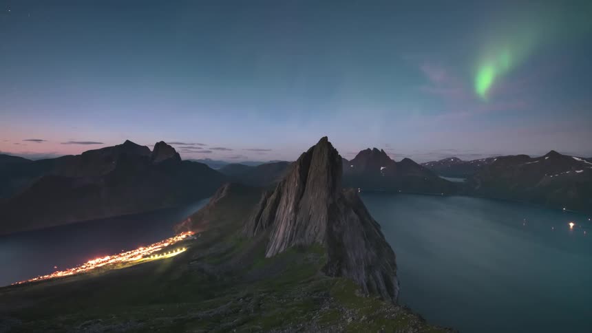 Panorama of rocky mountains by the sea against a sky with northern lights