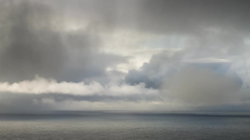 Storms including storm clouds move over an ocean