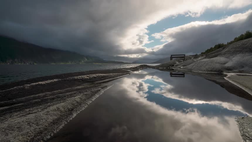 Receding river exposes mud under a rolling cloud filled sky