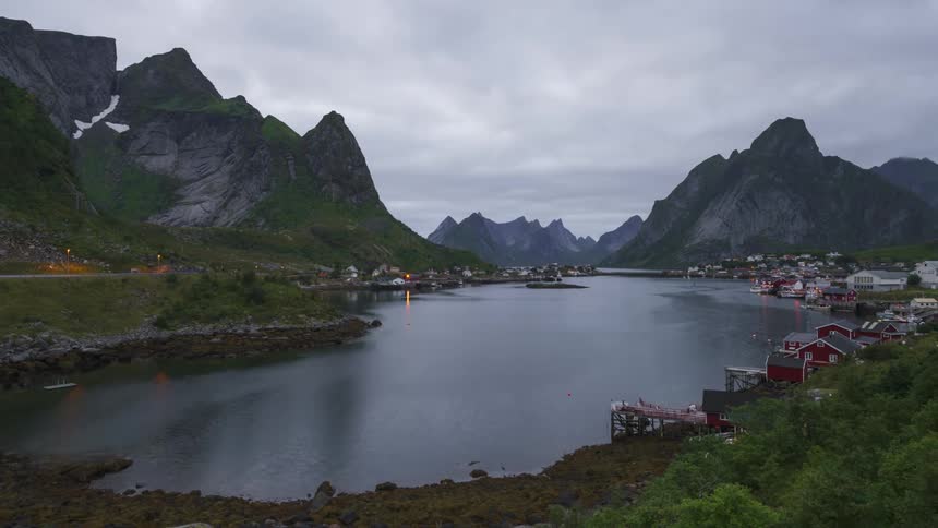 Natural landscape with houses in a village on the edge of a lake and surrounded by mountains on a cloudy day