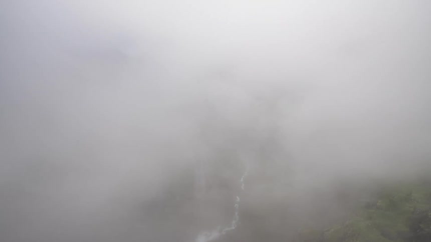 Clouds obscure a mountain valley with a hair pin road