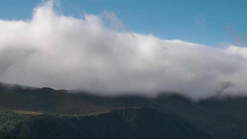 Sea of heavy clouds passing above rocky mountains