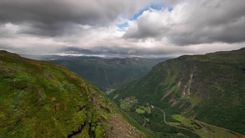 Hazy clouds passing above a greenish mountain valley