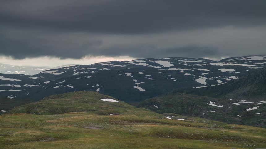 Mountain landscape with snow and black clouds passing by