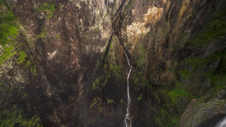 Waterfalls flow down the opposite walls of canyon on an overcast sky