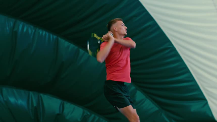 A young man plays tennis in slow motion