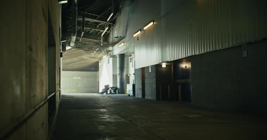 Wide bright corridor of an industrial building with concrete and metal walls and columns