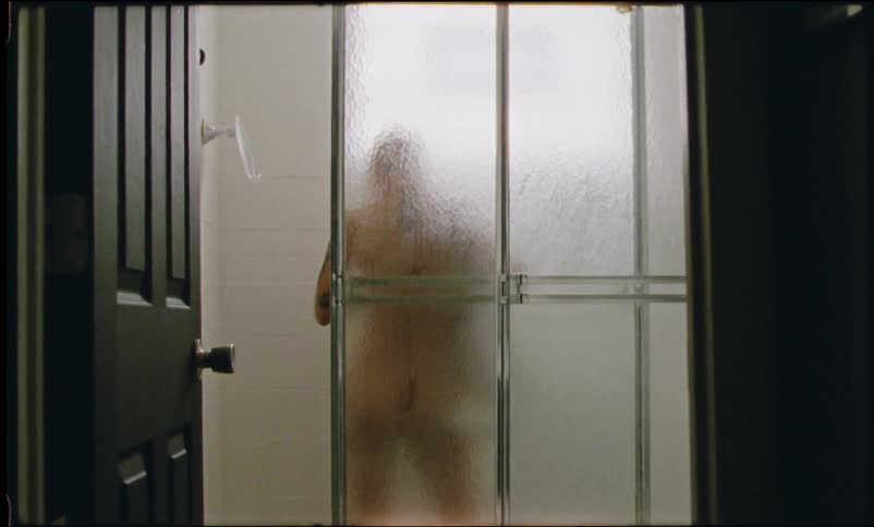 A person wipes off in a shower and then wraps a towel around their private parts