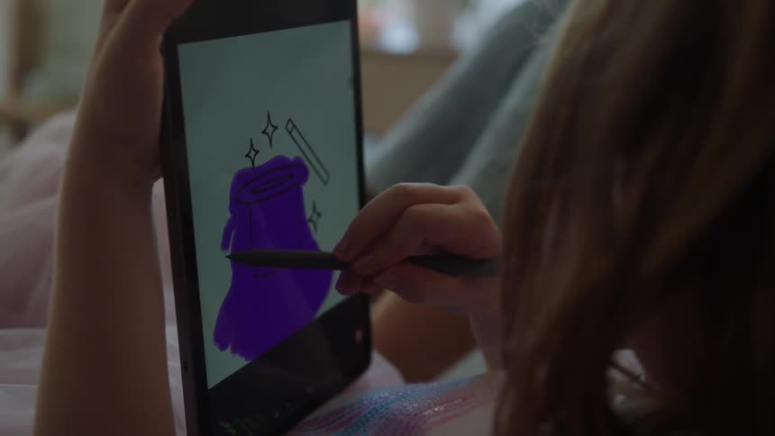 Child sitting drawing on a tablet