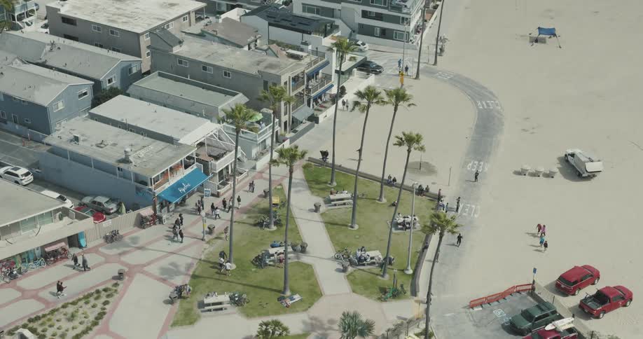 Aerial view of a coastal urban area with small park with green grass and palm trees
