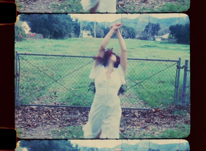 Woman twirls in front of a chain link gate
