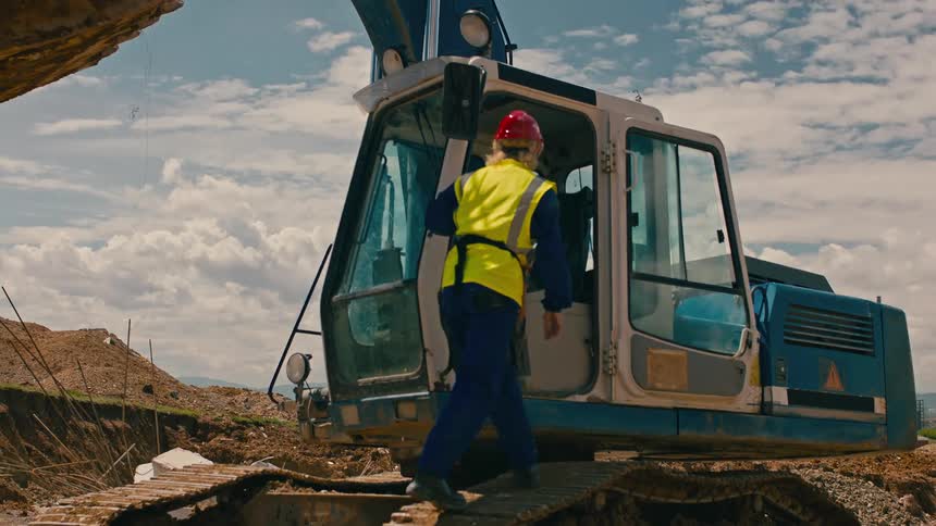 A construction worker enters the excavator