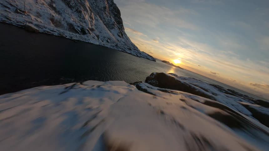 Sunrise seen from a low perspective over water with snowy mountains