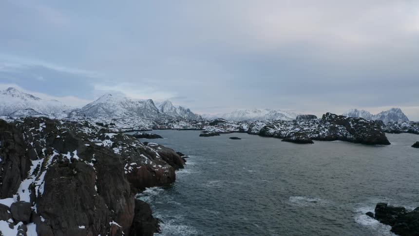 Aerial panorama of snowy mountains by the sea on a cloudy day