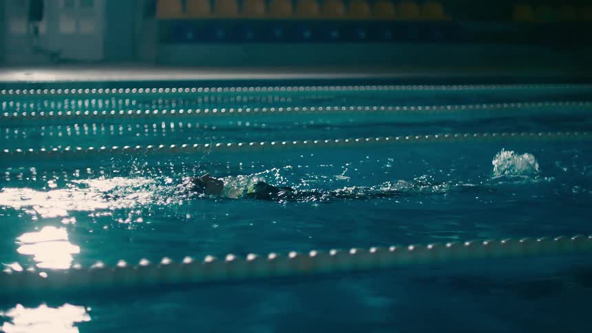 Woman swimming backstroke in an indoor swimming pool