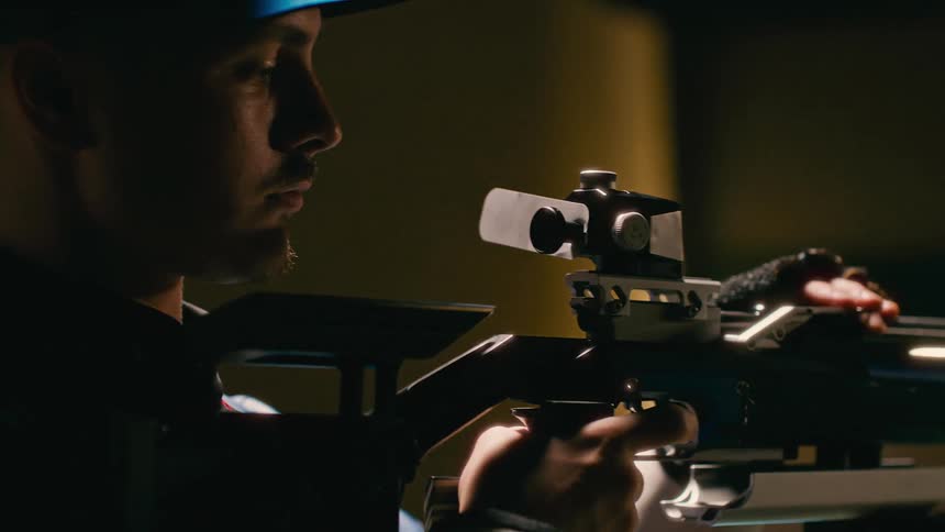 A man is holding a weapon and aiming with it