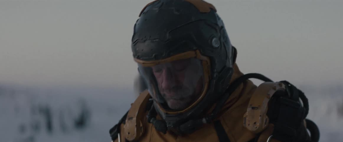 Astronaut looks down and bends over slightly