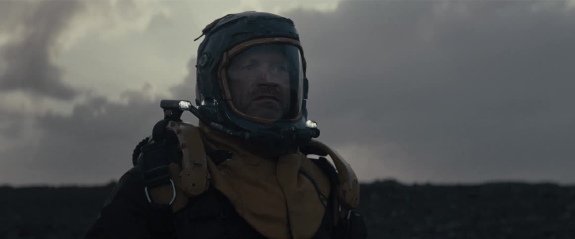 A man with a helmet and thick protective clothing using a technological device pointing forward