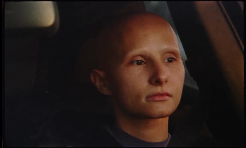 A bald woman drives a car