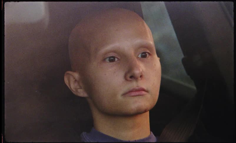 Portrait of a young bald woman driving