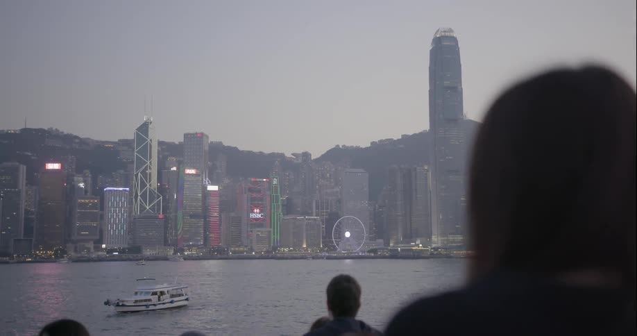 People on shore look across at the hong kong skyline