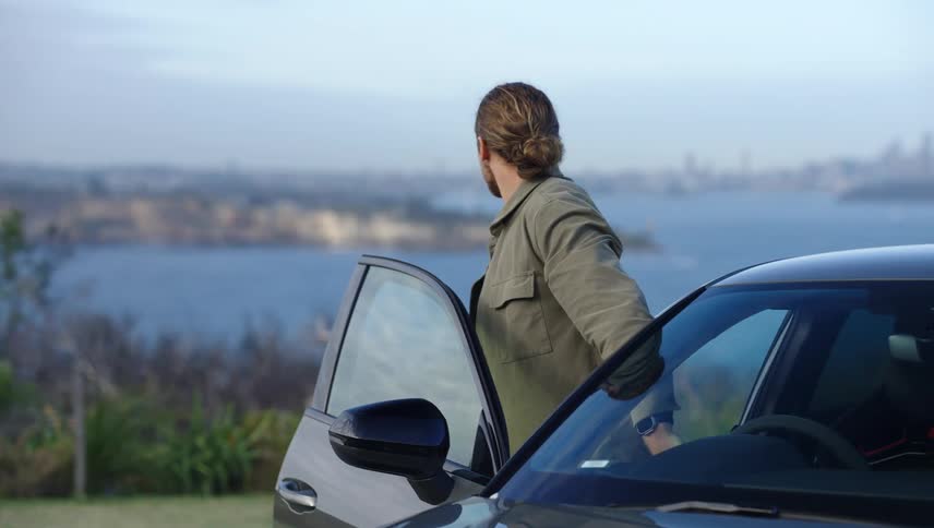Man getting out of the car with a panoramic seaside view
