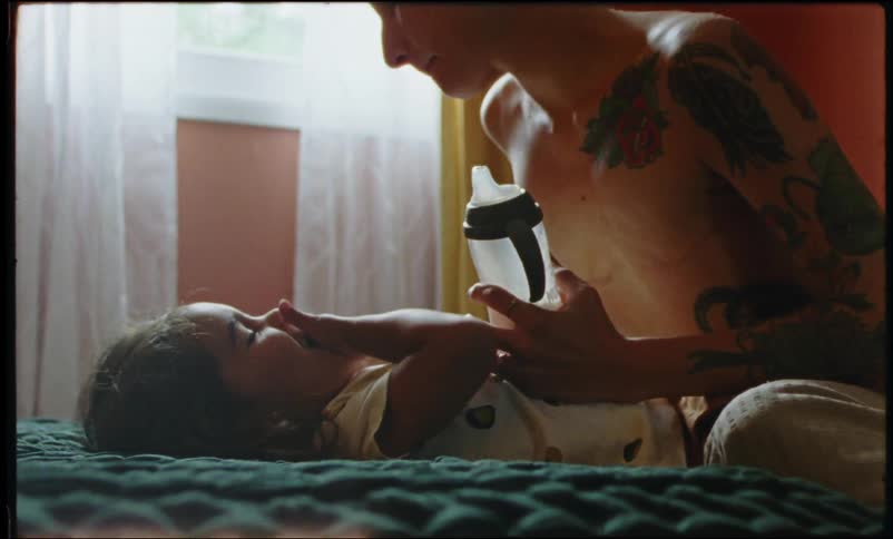 A mother gives her daughter a drink of water in a bedroom