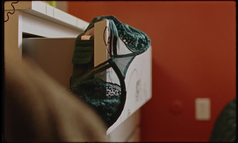 Blue lacey bra hanging off the corner of a dirty open drawer