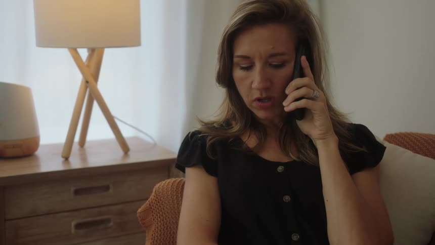 A woman sitting on a couch and talking to someone on the phone