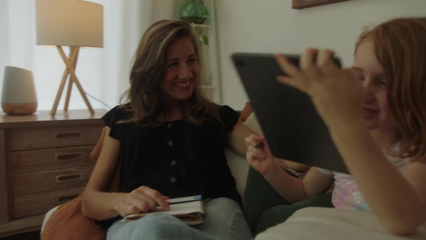 Mother working from home relaxes with her daughter in the couch