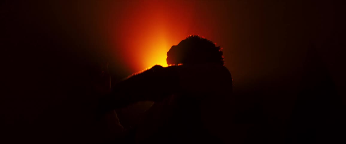 Person dances in front of a bright orange light casting light rays and shadows as they move