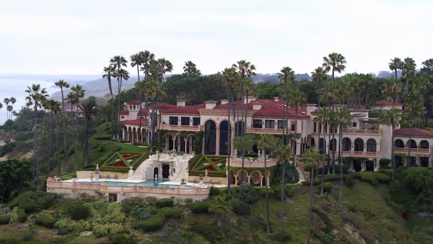 A large estate with a pool sits on elevated land near a coast