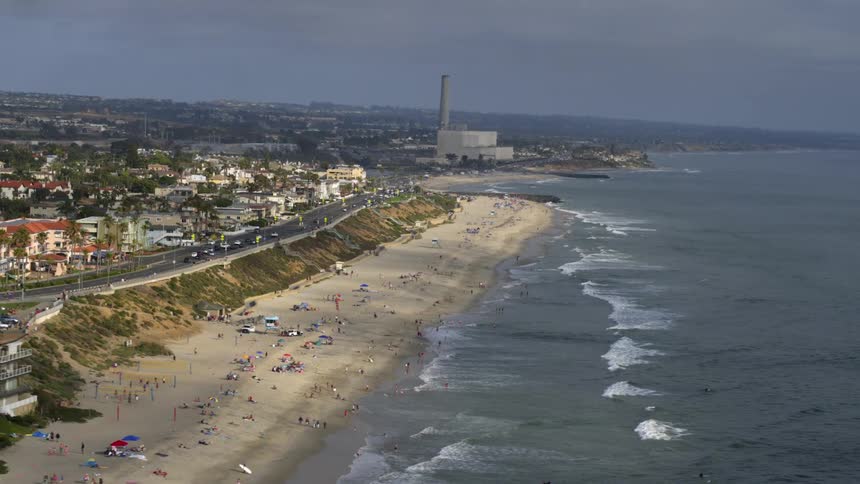 Aerial view of a beach with gentle waves and the presence of bathers on the coast of a city