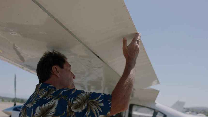 Man examines the wing of a small plane