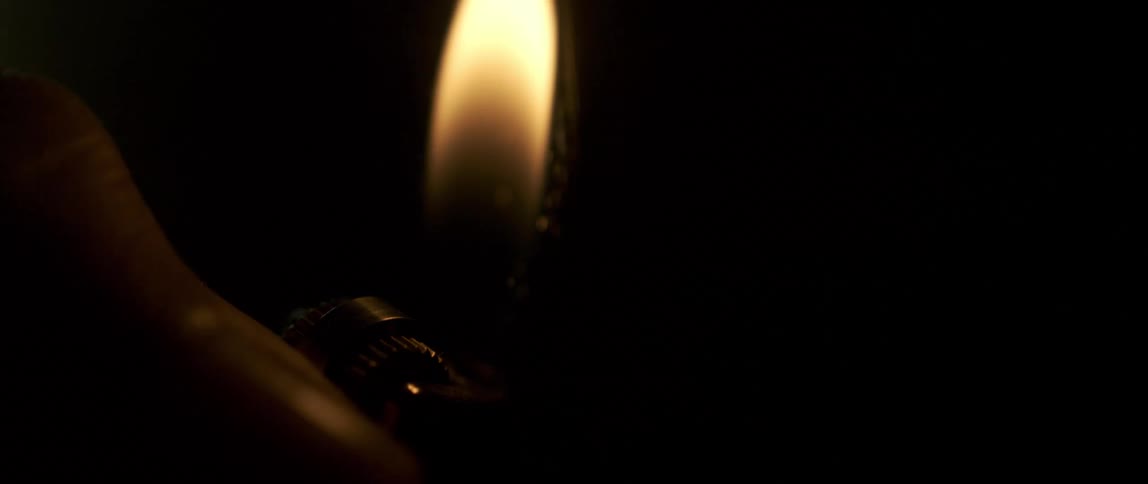 Close up of a lighter sparkling before lighting a flame on a dimly lit room
