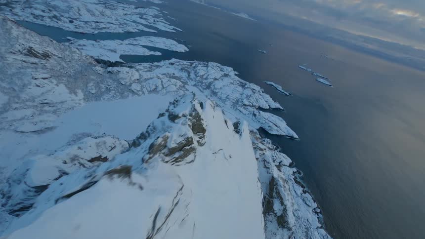 Aerial scenery of snowy mountains by the sea an glaciers in a cloudy sky