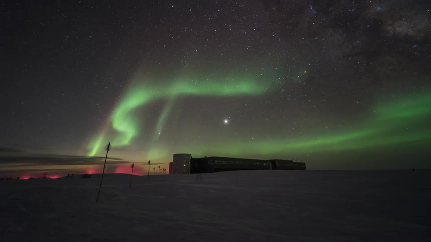 An aurora lights up a night sky over a research facility