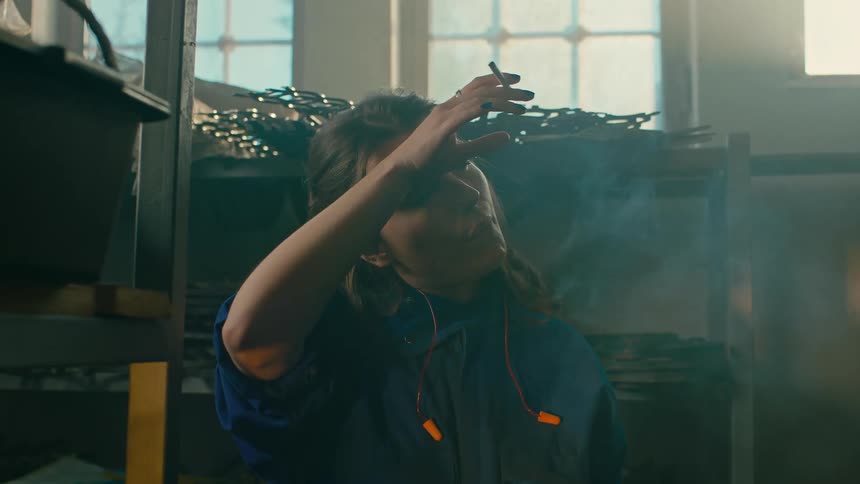 Man lighting his coworkers cigarette inside a factory