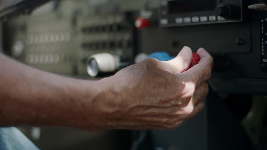 Hand pressing a red button on an indoor desktop