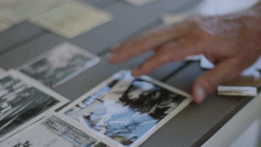 An elderly person puts a photograph down on a table