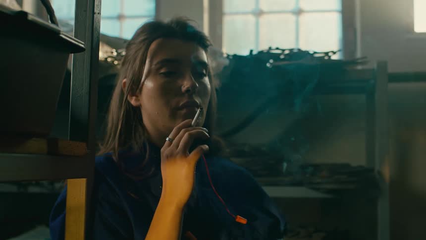 A factory worker takes a break to smoke in the warehouse