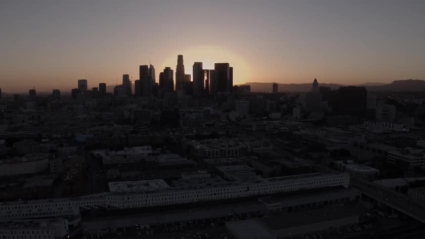The sun sets over city buildings and skyscrapers